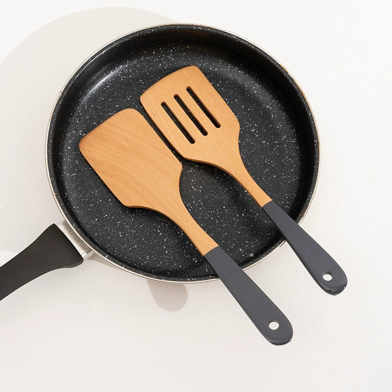 Wooden cooking utensils resting in a nonstick cookware pan