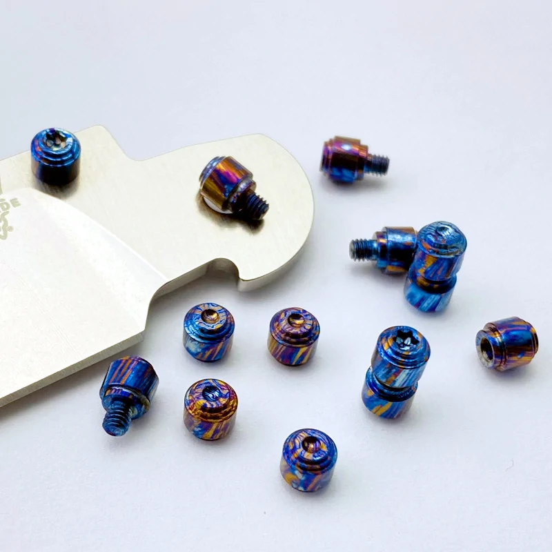 Titanium Damascus knife thumb stud accessories on a white background